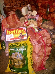 A pile of bags of different wood fuels logs briquettes heat logs - Wood Fuel Co-operative