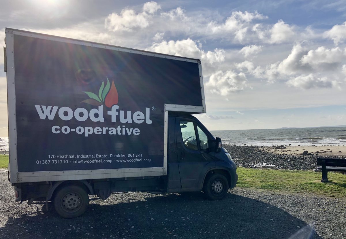 The Wood Fuel Co-operative delivery van parked by the sea in Scotland - Wood Fuel Co-operative